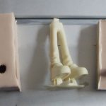 Duas metades de uma fôrma de silicone com peça moldada em resina entre elas