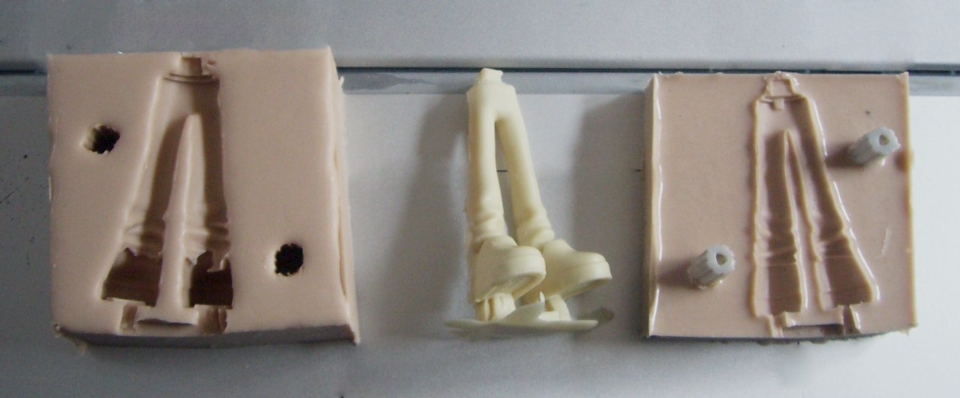 Duas metades de uma fôrma de silicone com peça moldada em resina entre elas